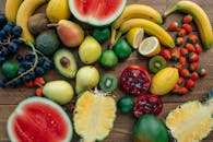 A colorful assortment of fresh fruits including bananas, strawberries, and watermelon arranged on a wooden table.